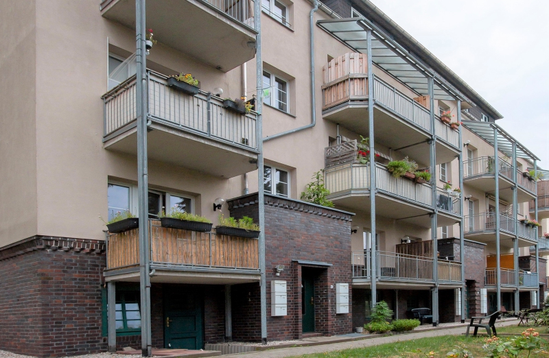 Das Bild zeigt ein oranges Etagenwohnhaus mit Balkonen in Chemnitz an einem bewölkten Tag.