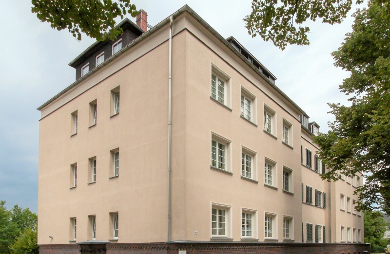 Das Bild zeigt ein oranges Etagenwohnhaus in Chemnitz an einem bewölkten Tag.