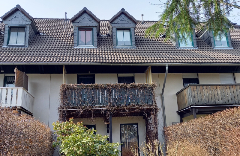 Dieses Bild zeigt ein weißes Reihenmittelhaus mit Balkon in Stollberg an einem hellen Tag unter blauem Himmel.