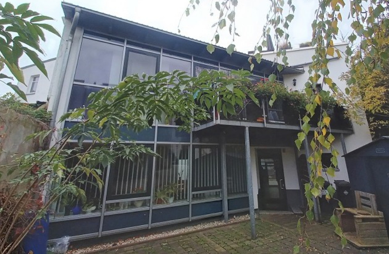 Dieses Bild zeigt ein blaues Wohn- und Geschäftshaus mit Balkon in Stollberg an einem bewölkten Tag.